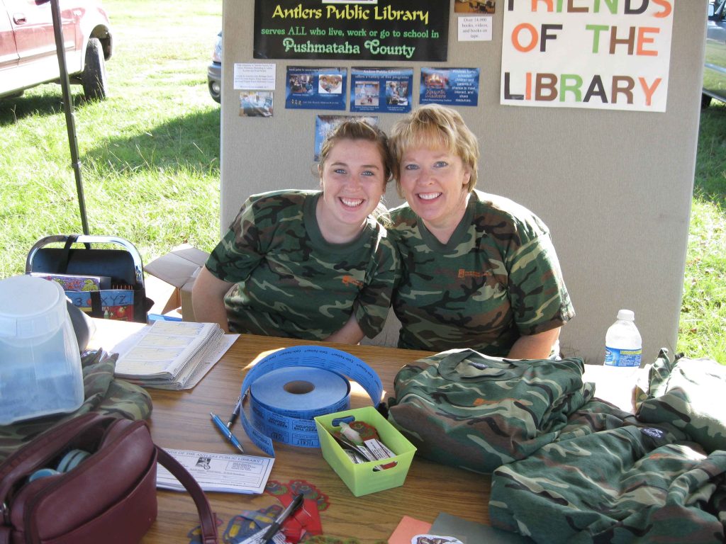 Friends sitting at Deer Festival booth.